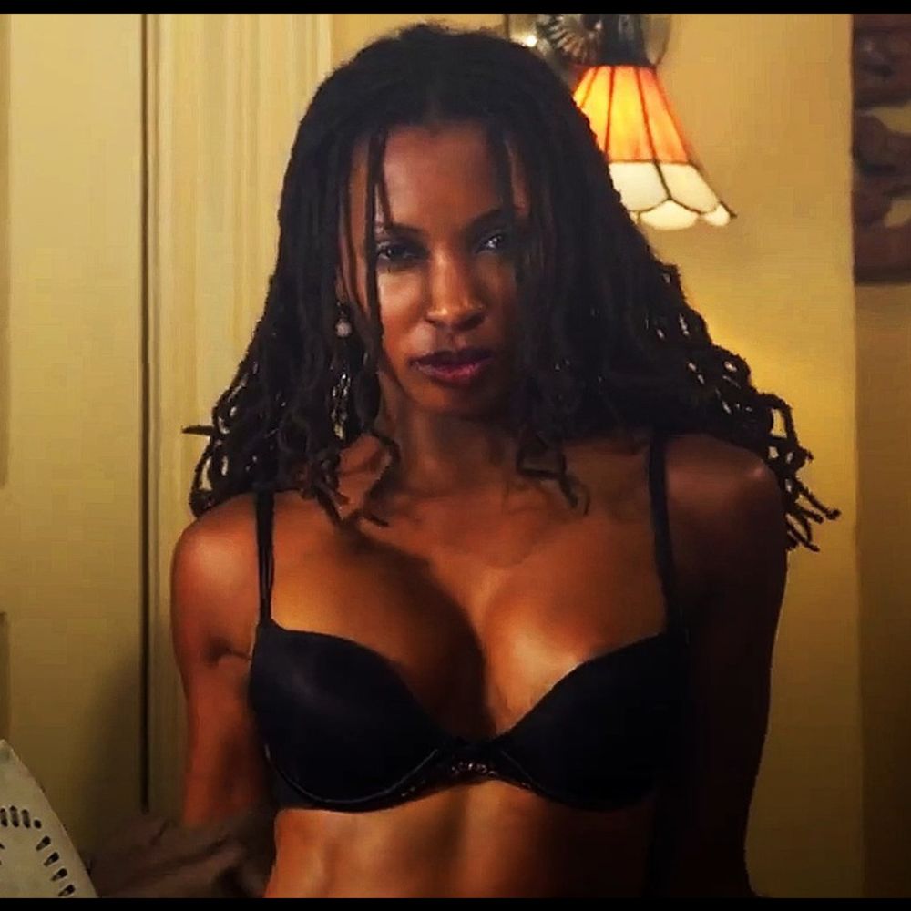 Woman with shoulder length dreadlocks coming out of shirt to reveal black bra underneath 