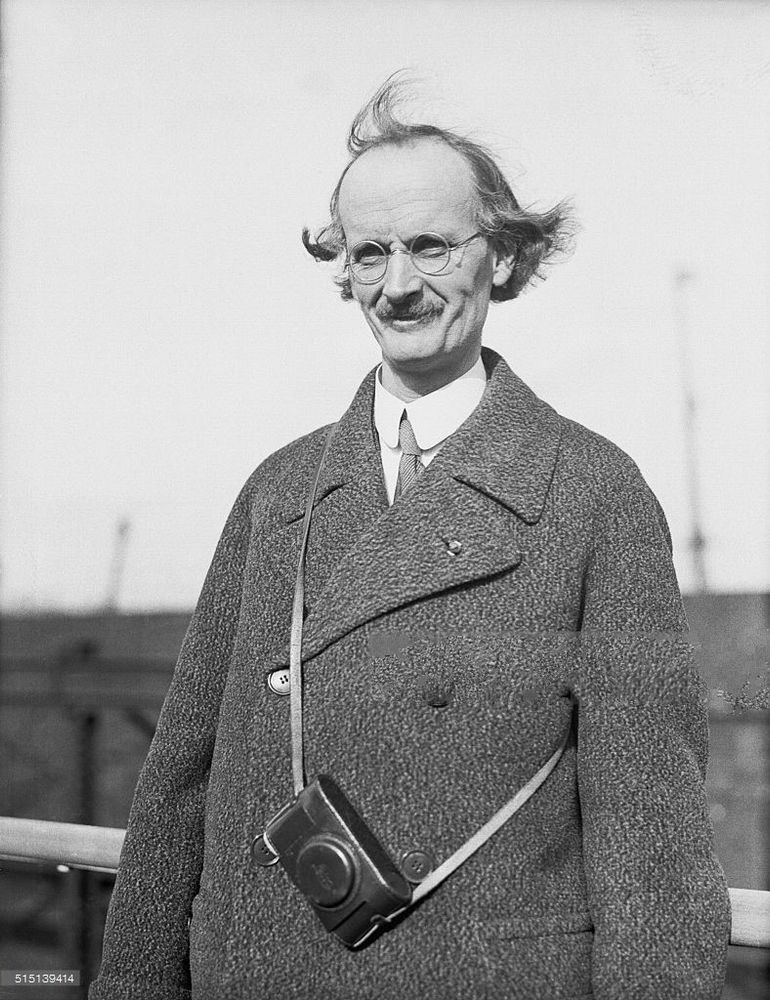 A very tall Swiss physicist from the early to mid twentieth century, with a distinctive look - round glasses, moustache, male pattern baldness, overcoat.