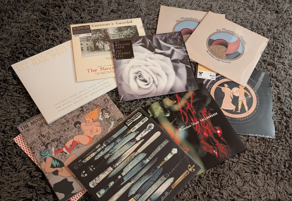 A collection of Mountain Goats lps arranged in a grey rug