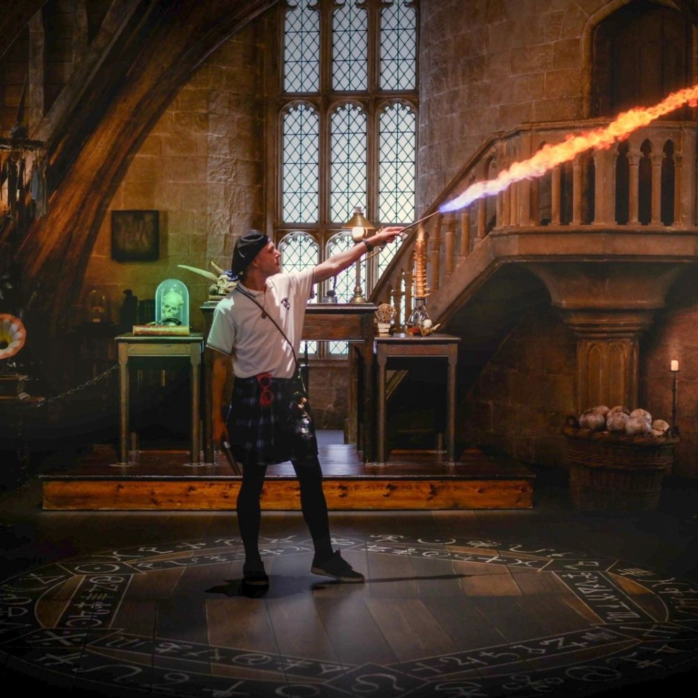 a guy in Ravenclaw style clothes is standing in the defense against the dark arts classroom at the Warner Bros Studio Tour Tokyo and casting a fire spell