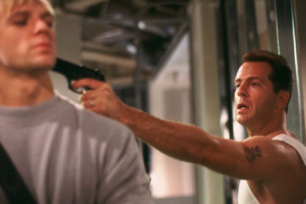 A still from Die Hard. John McClane holds up a terrorist. 