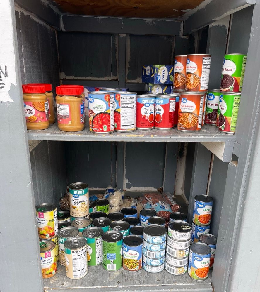 Canned food like beans, peanut butter & other items inside a pantry.