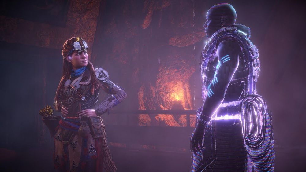 Screenshot from Horizon Zero Dawn Aloy and a hologram of Sylens looking at each other in a dimly lit cave