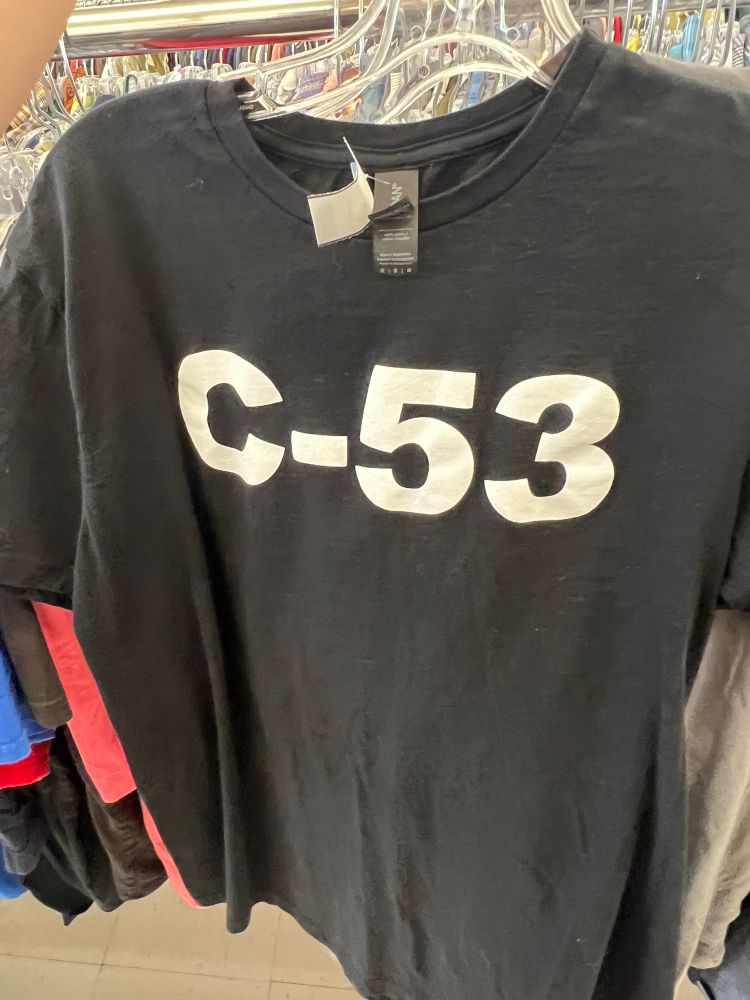 a black t-shirt in a thrift store that simply says “c-53” in bold text