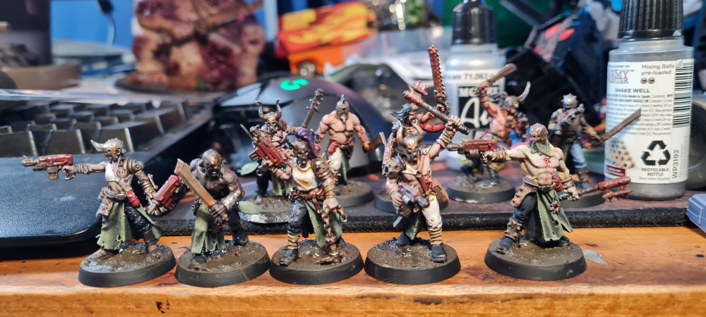 5 warhammer minis of human Cultists wearing green and white clothes, rusted iron armour and holding pistols and improvised melee weapons