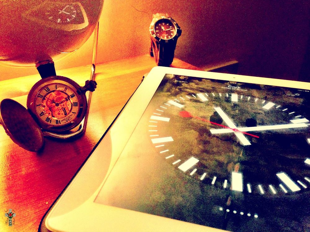 Photograph of a watch and two clocks on a table. By Mike Roth under a CC BY-NC-ND license: bit.ly/4fWrctm