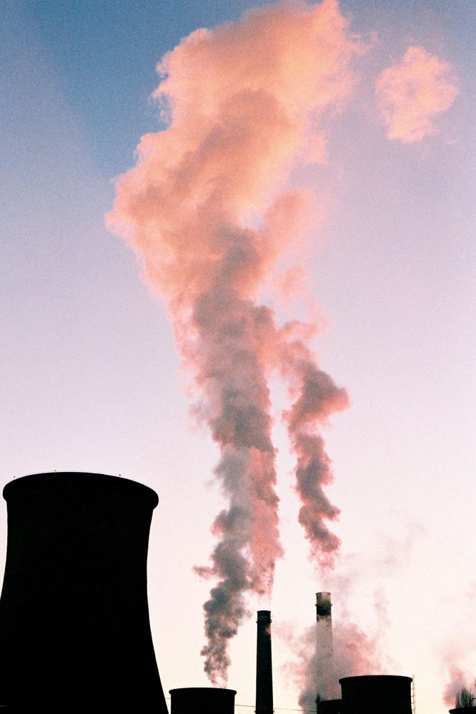 Photograph of industry chimneys emitting smoke. By Octavian Catană under a free Unsplash license: https://bit.ly/41LJcSe.