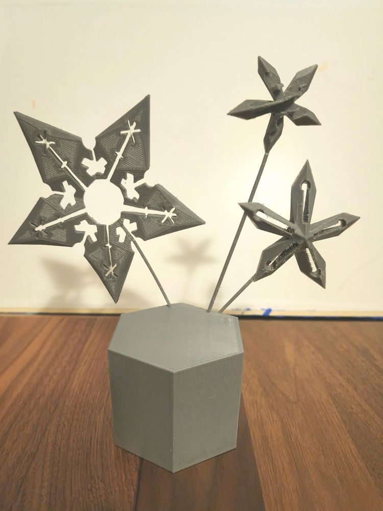 Small grey printed and modelled plinth, with 3 rough snowflakes attached and sticking up, vertical on white background
