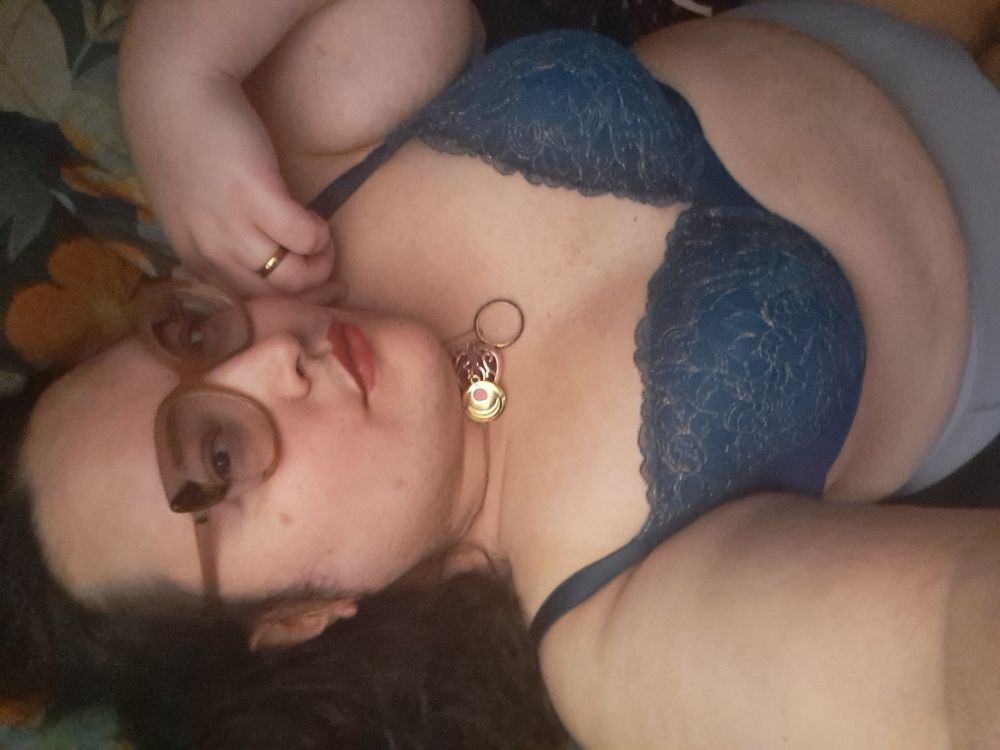 Dona laying in bed in her underwear being cute. Her necklace shines golden. 