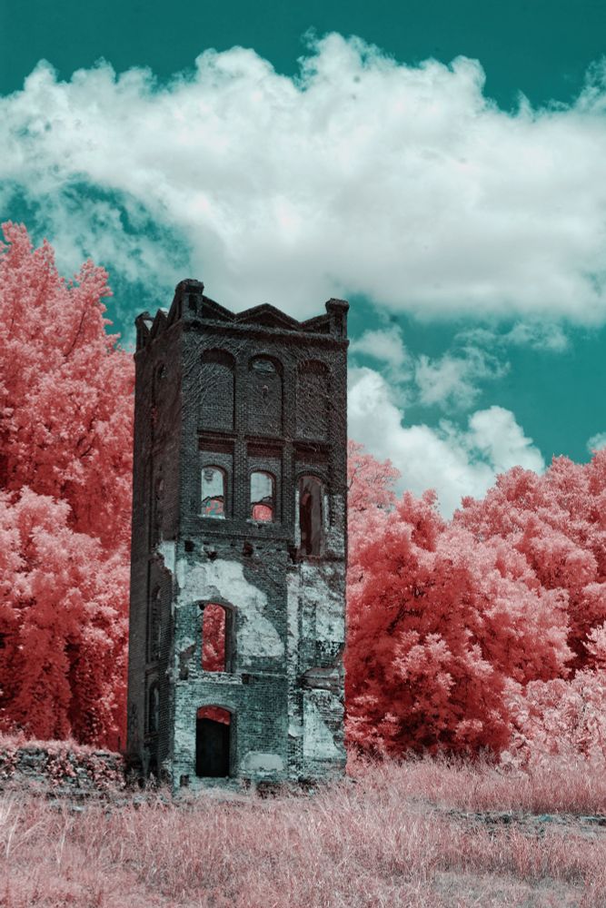 False color infrared photo of a brick tower in front of trees and clouds