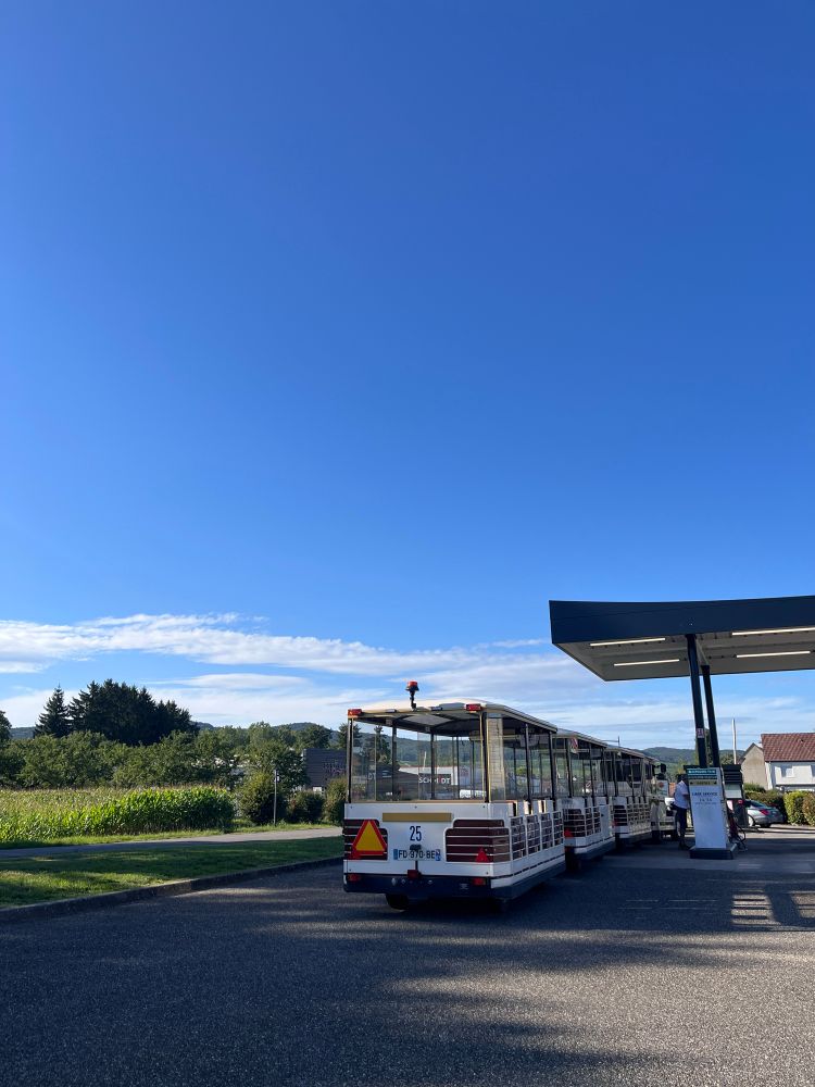 Touri-„Bahn“, also motorbetriebenes Dieselfahrzeug mit mehreren Ahängern für Passagiere, an einer Tankstelle. 