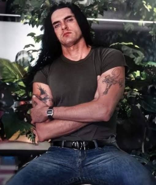 Peter Steele, a very tall, well-built man of Scandinavian descent. He is pale, with long, dark hair to his waist, a strong brow and cheekbones, straight nose, and generous lips. Although you cannot see it in this particular picture, his eyes are blue (though he commonly wore green contacts in promo pictures).

He is sitting on the roof of his car, legs spread and arms crossed casually, with a slightly oerturbed expression on his face, as if he doesn't really want to be there.

Not pictured:  his extremely deep voice with heavy Brooklyn accent. (lol)