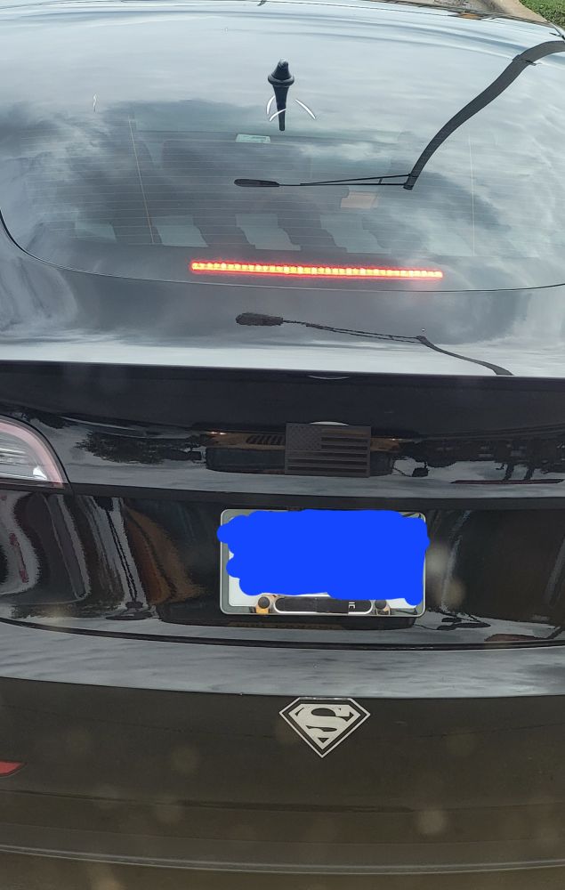 A tesla hidding it's logo with a black American flag and black electrical tape on license plate frame. Point and laugh.