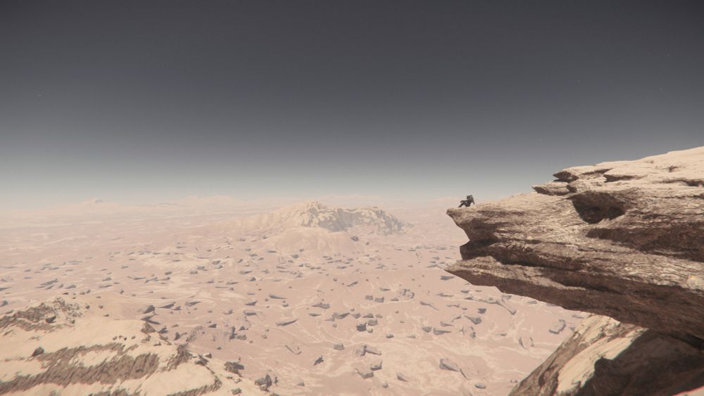 Une personne au loin est assise sur un gros rocher qui cache une partie du décors. Au loin, les déserts d'une lune de Crusader (Système Stanton) se dessinent. 