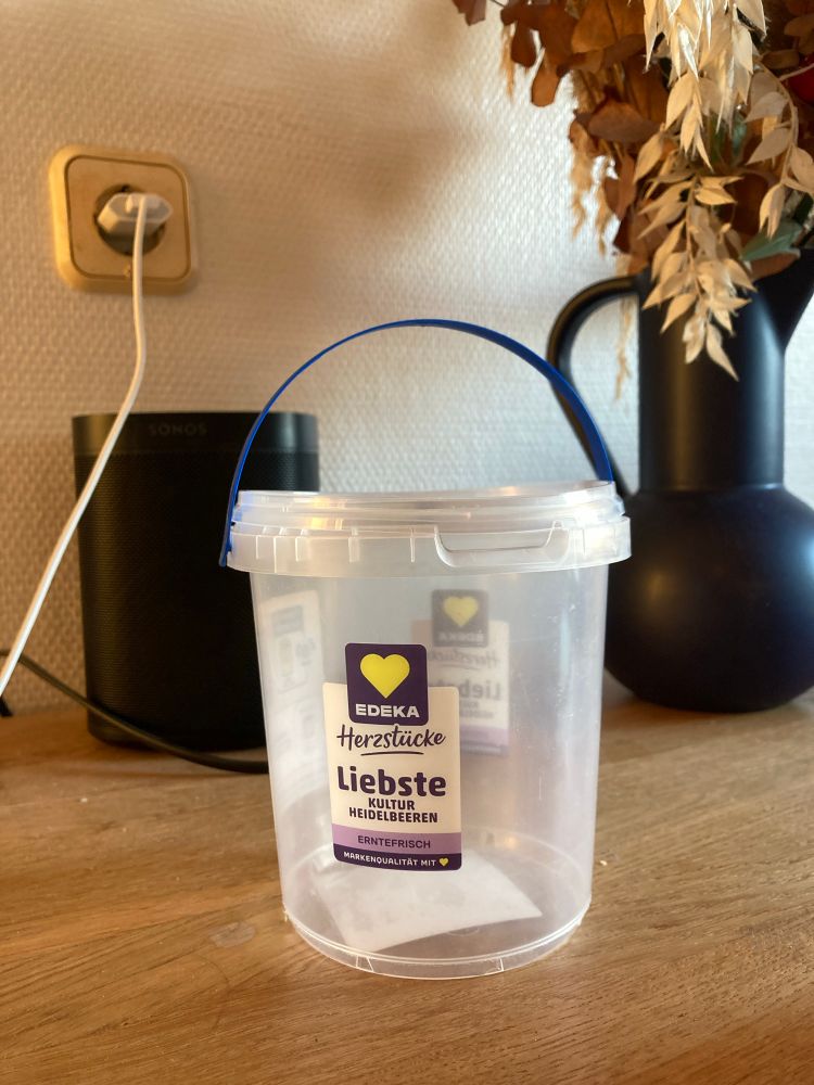 Ein leerer Heidelbeer-Plastikeimer auf Tisch. Man sieht Herzen auf der Verpackung und liest liebste und herzlichst