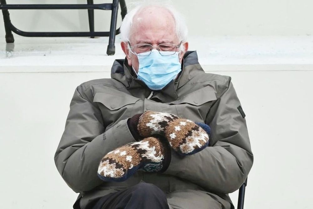 Super senator Bernie Sanders seated wearing a thick coat and mittens