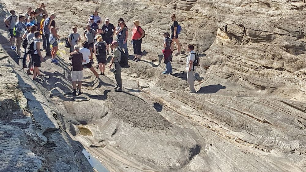 A group of people wearing backpacks stand on a rocky landscape.