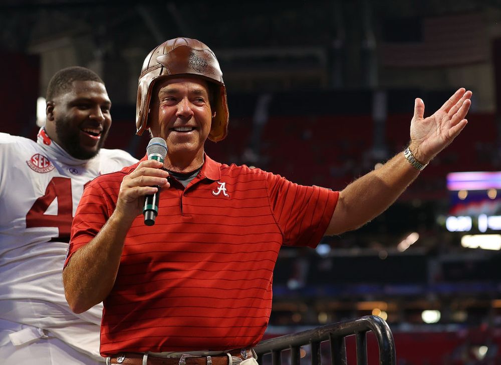 Coach Nick Saban wearing an old timey football helmet. 