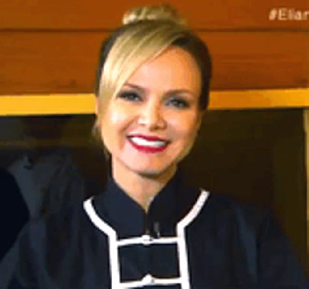 a woman with blonde hair and red lips is smiling and wearing a black shirt with white trim .