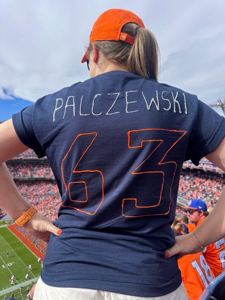 Blonde at broncos game wearing a homemade number 63 shirt 