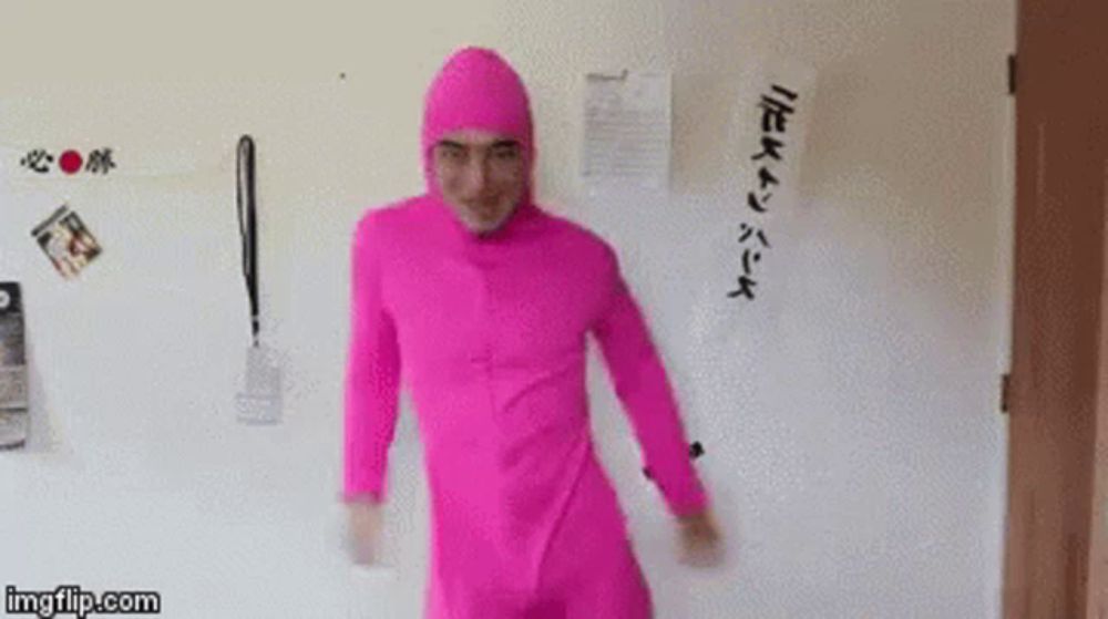 a man in a pink suit is dancing in front of a wall .