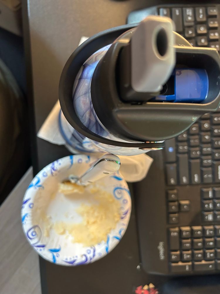 A bowl of mashed potatoes sits next to a water bottle. 