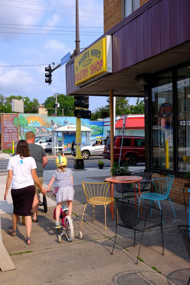 A family walks past a cafe storefront on a street corner in Minneapolis. 