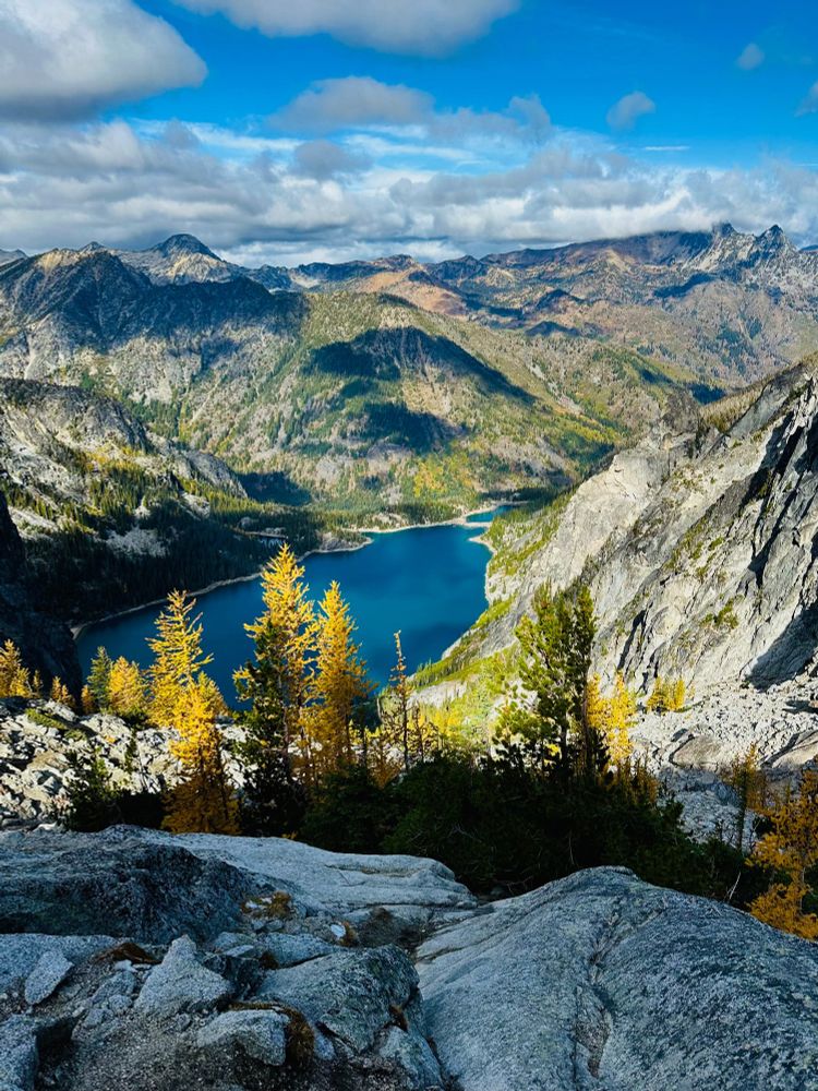 A mountain lake, viewed from pass, golden colored larches growing on the steep slopes below