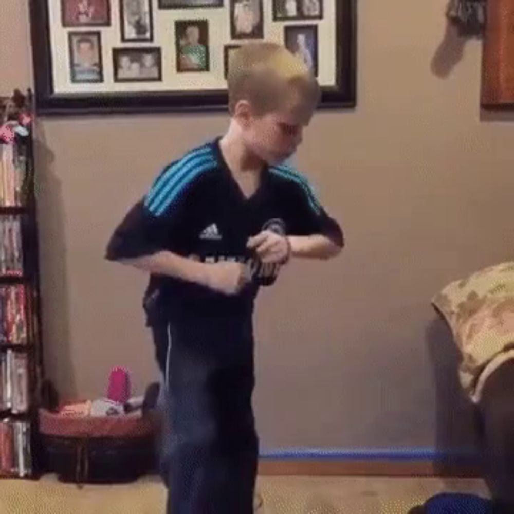 a young boy wearing an adidas shirt is dancing in a room