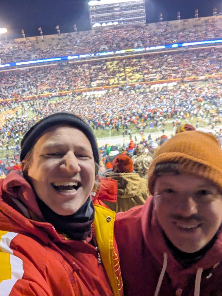 Ian and his buddy Rob, in a stadium with a rushed field in the background