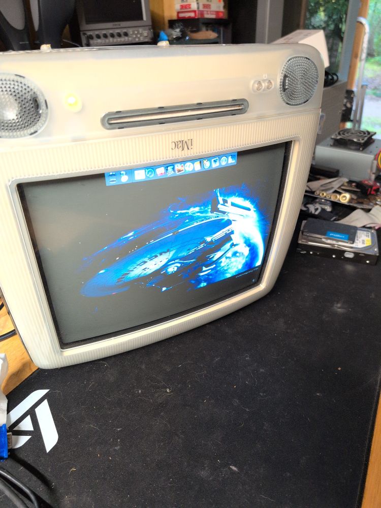 An inverted iMac G3. It is powered on.