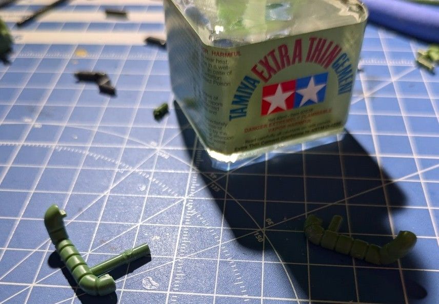 A piece of the SDCS Zaku-II gunpla accidentally cut in half. To add insult to injury the part I cut out vanished so I had to repurpose another piece of runner and measure it to fit. There's also a jar of Tamiya extra thin cement.