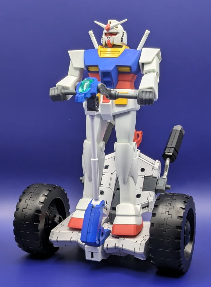 The Best Mecha Collection RX-78-2 Gundam 'Revival Ver.' gunpla riding on the 30 Minutes Missions 'Wheel Mobile' model. Both are fully painted, the Gundam in the usual colors and the weird Segway thing painted to match the Gundam except with sick chrome exhaust pipes.