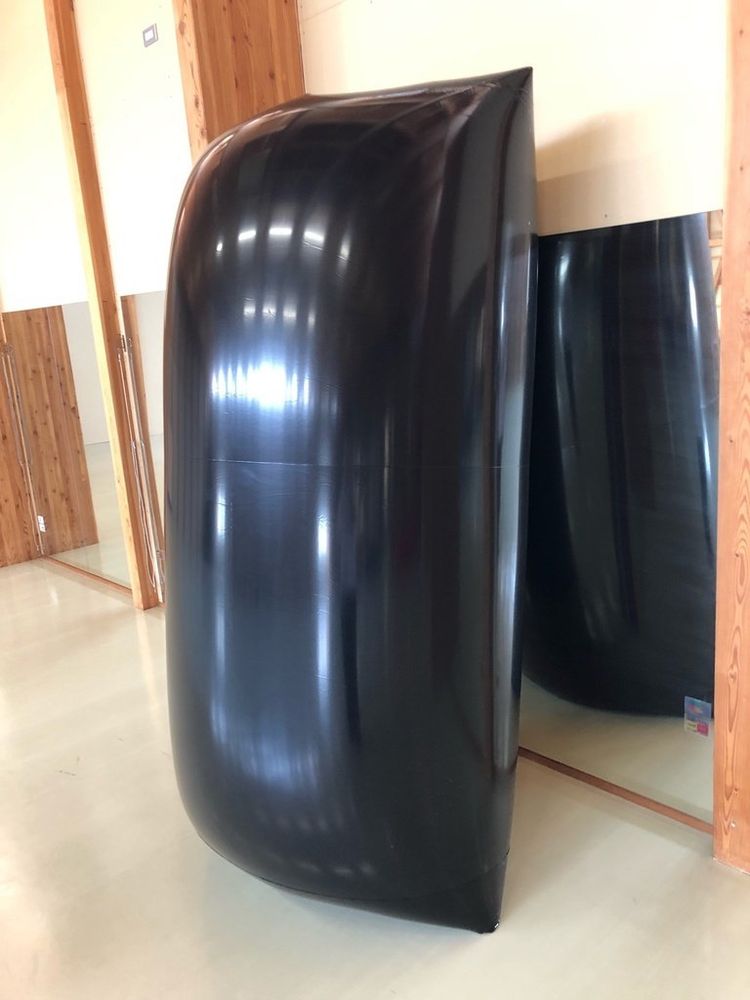A large black inflatable torus. It is shiny.