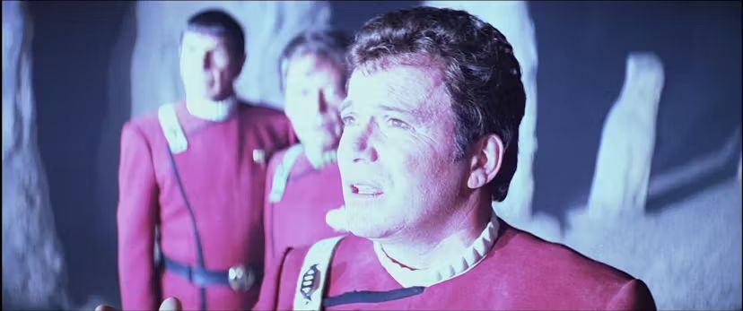 A man looking into the light with two other men behind him all wearing similar uniforms.

William Shatner, DeForest Kelly, and Leonard Nimoy are Capt. Kirk, Dr. McCoy, and Mr. Spock on Star Trek.