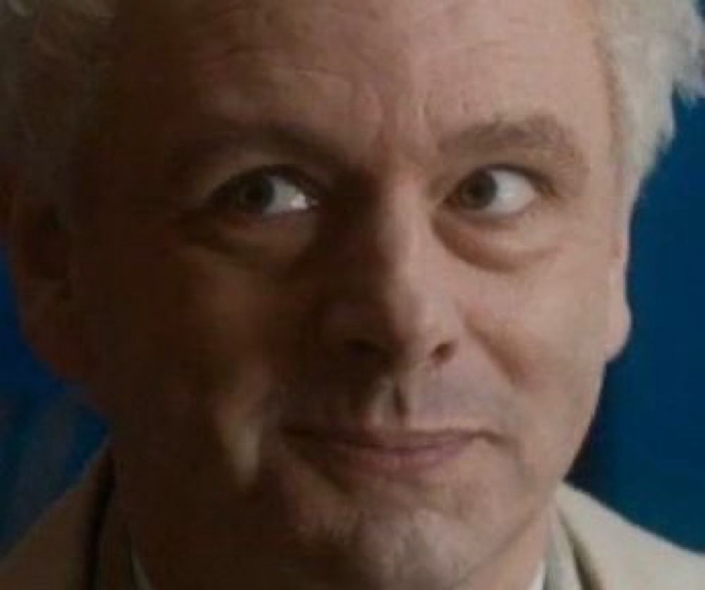 Close up of Aziraphale's face. He is look up and to the viewer's left. He has an impish expression. 