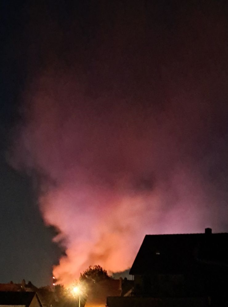 Große Rauchwolke hinter Häusern im Nachthimmel.