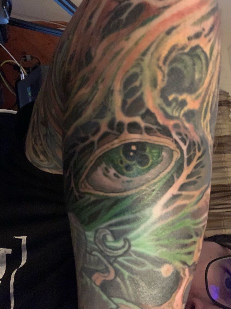 A fresh eye tattoo that has multiple purples and a green iris 