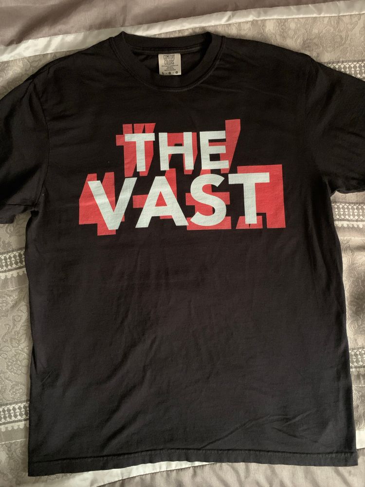 A black t-shirt which reads ‘The Vast’ in white font on-top of a fake Akira-style backing font in red. 