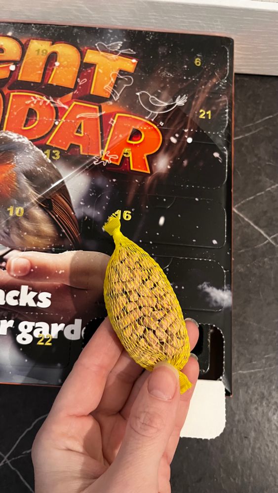 A small packet of suet bird food pellets in a plastic yellow net bag 