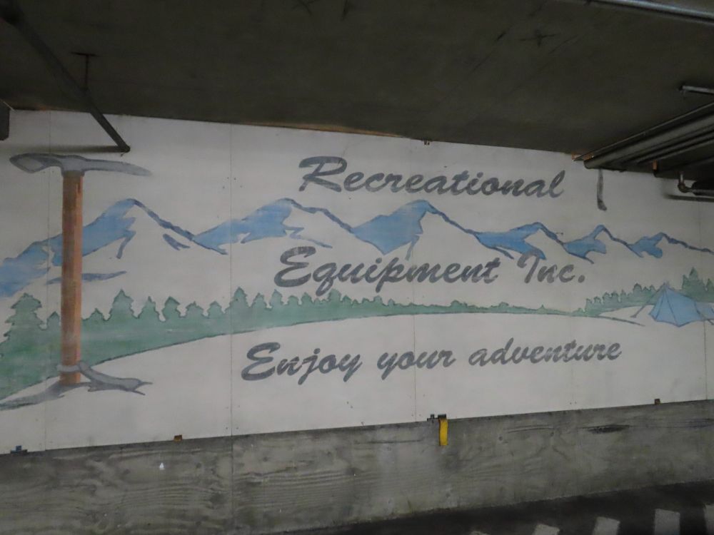 Sign with mountains and trees saying "Recreation Equipment Inc. Enjoy your adventure"