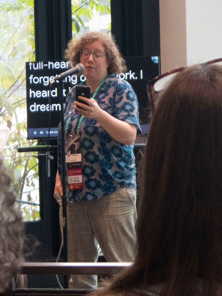 A woman reading from her phone for an audience