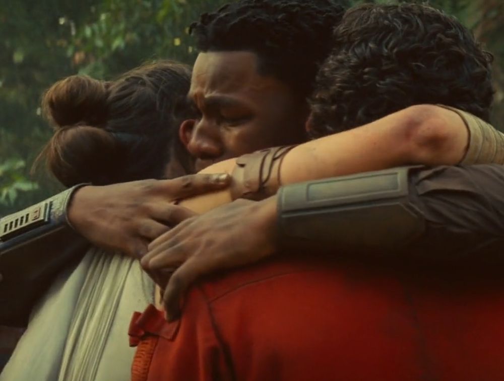 Finn hugging Rey and Poe. He looks sad, in tears.