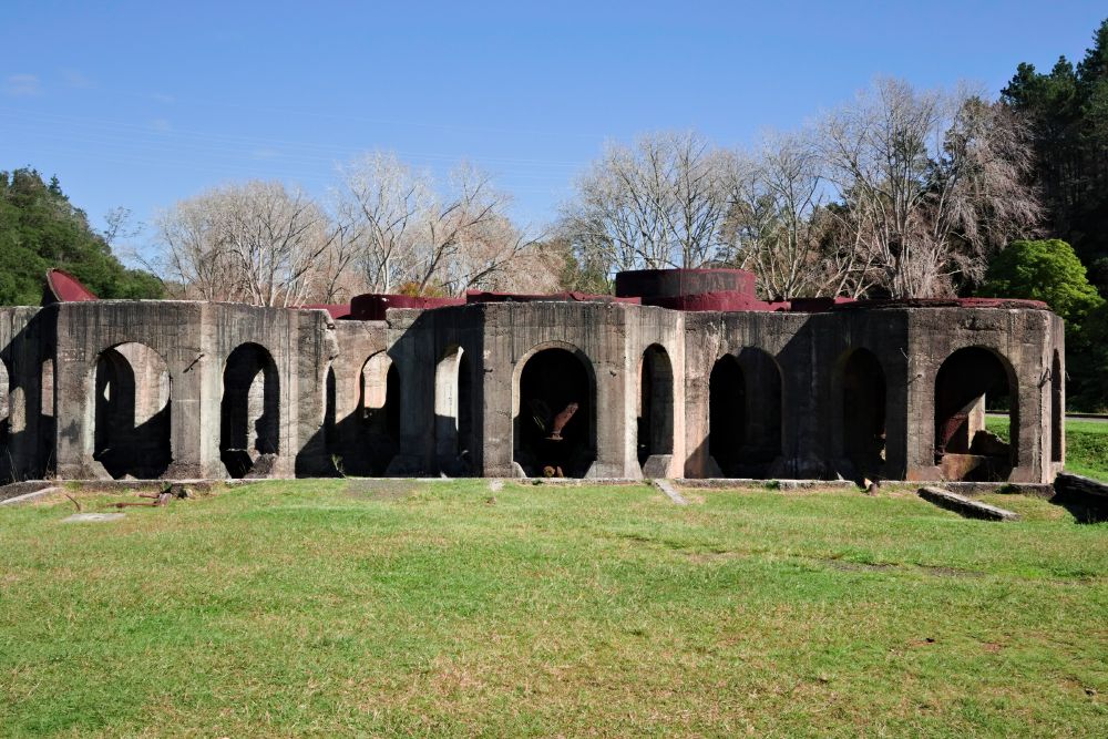 Stone ruins of Mt Victoria Battery, with lush green lawnlike grass below and blue sky above.