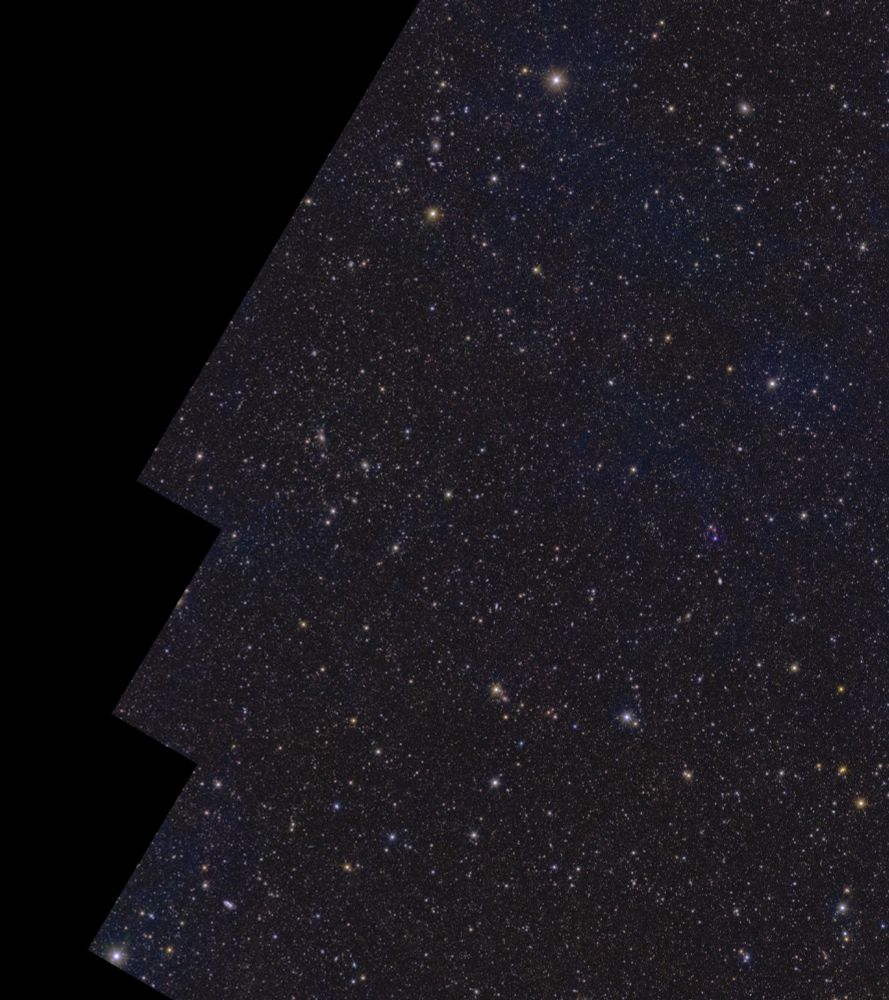On a black background lies a rectangular shape with several stepped notches cut out of its corners, oriented with its longest edges running from bottom left to top right. Contained within the shape are more than ten million galaxies, and stars of various size, brightness and colour. Wispy faint blue cloud-like structures permeate the image, representing gas and dust in between the stars in our own galaxy.