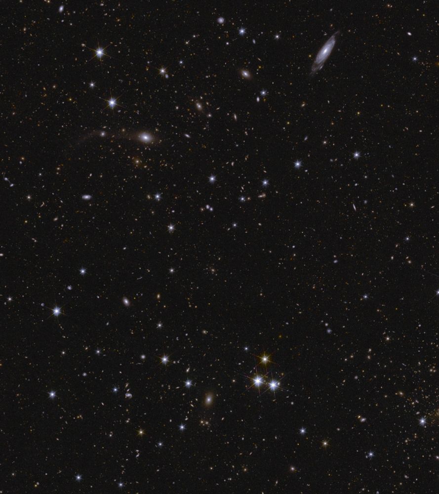 LEFT - Image description: A sea of stars and galaxies sparkle against a black background. Several galaxies can be identified by their elongated shape and/or spiral arms. Some galaxies are seen edge-on while one prominent spiral galaxy at the bottom centre is seen face-on. At the far right, between the middle and top of the image, are some interacting galaxies. Galaxy clusters are also seen, in particular near bottom centre, where features smeared into arcs represent gravitational lensing. The brightest stars in the image have diffraction spikes.]