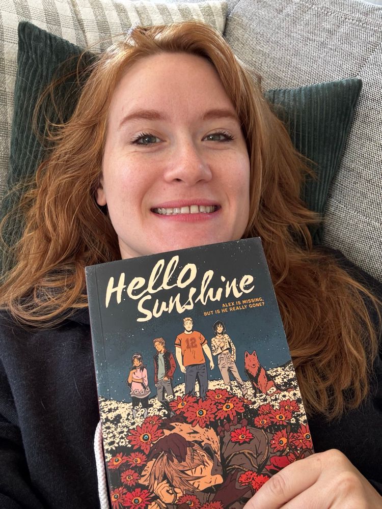 A selfie of me holding up the graphic novel “hello sunshine”