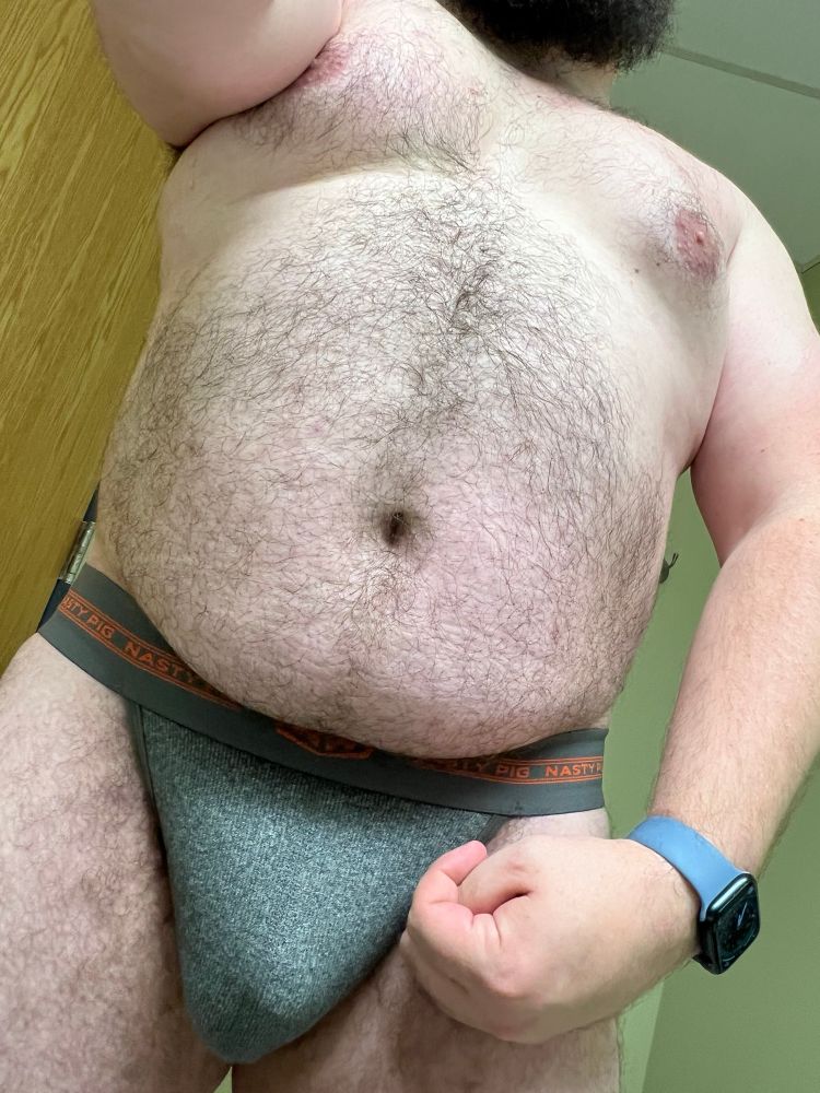 a bearish man wearing a gray jockstrap photographed from bulge level