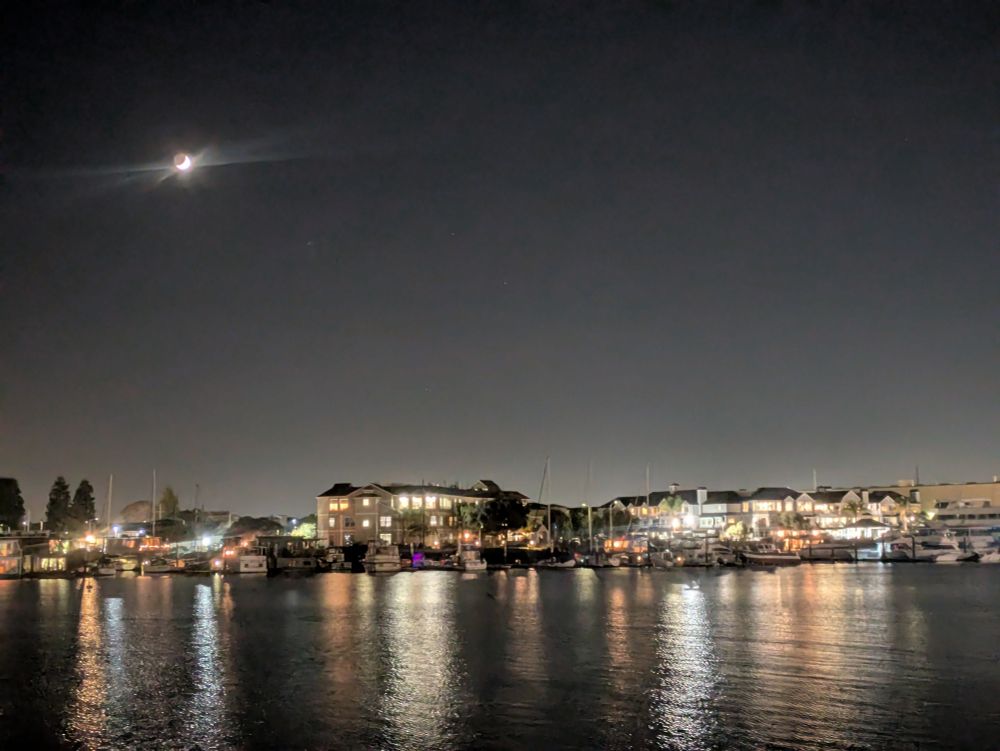 Buildings on the water, moon in the sky 