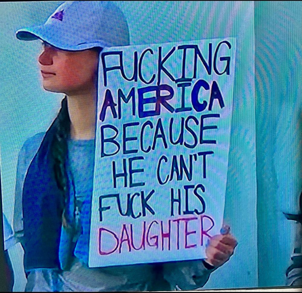 Protestor holding a sign that says “Fucking America because he can’t fuck his daughter”.